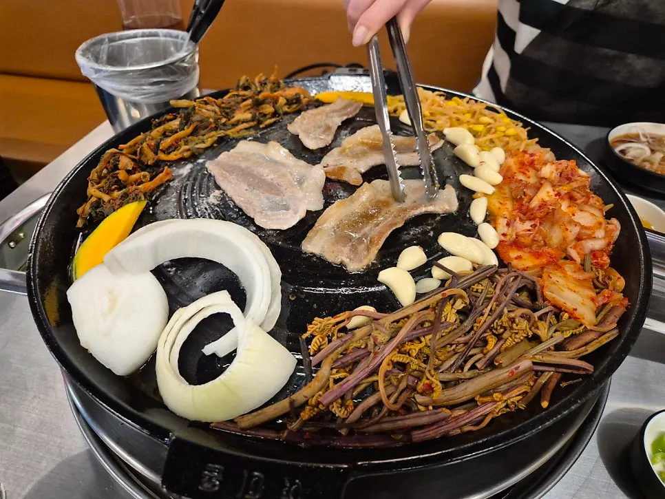 Staff grilling pork neck on the cauldron-lid grill