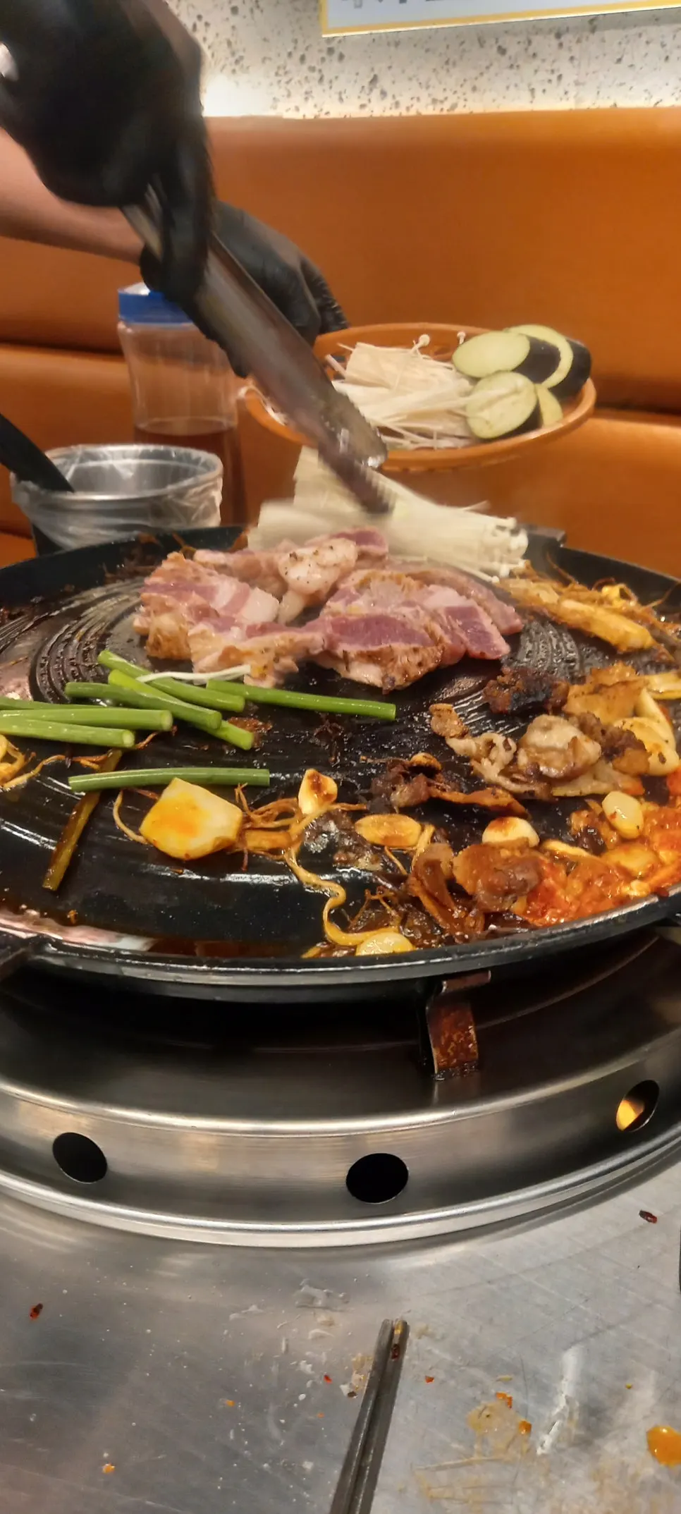 Vertical shot of sizzling cauldron-lid meat and side dishes