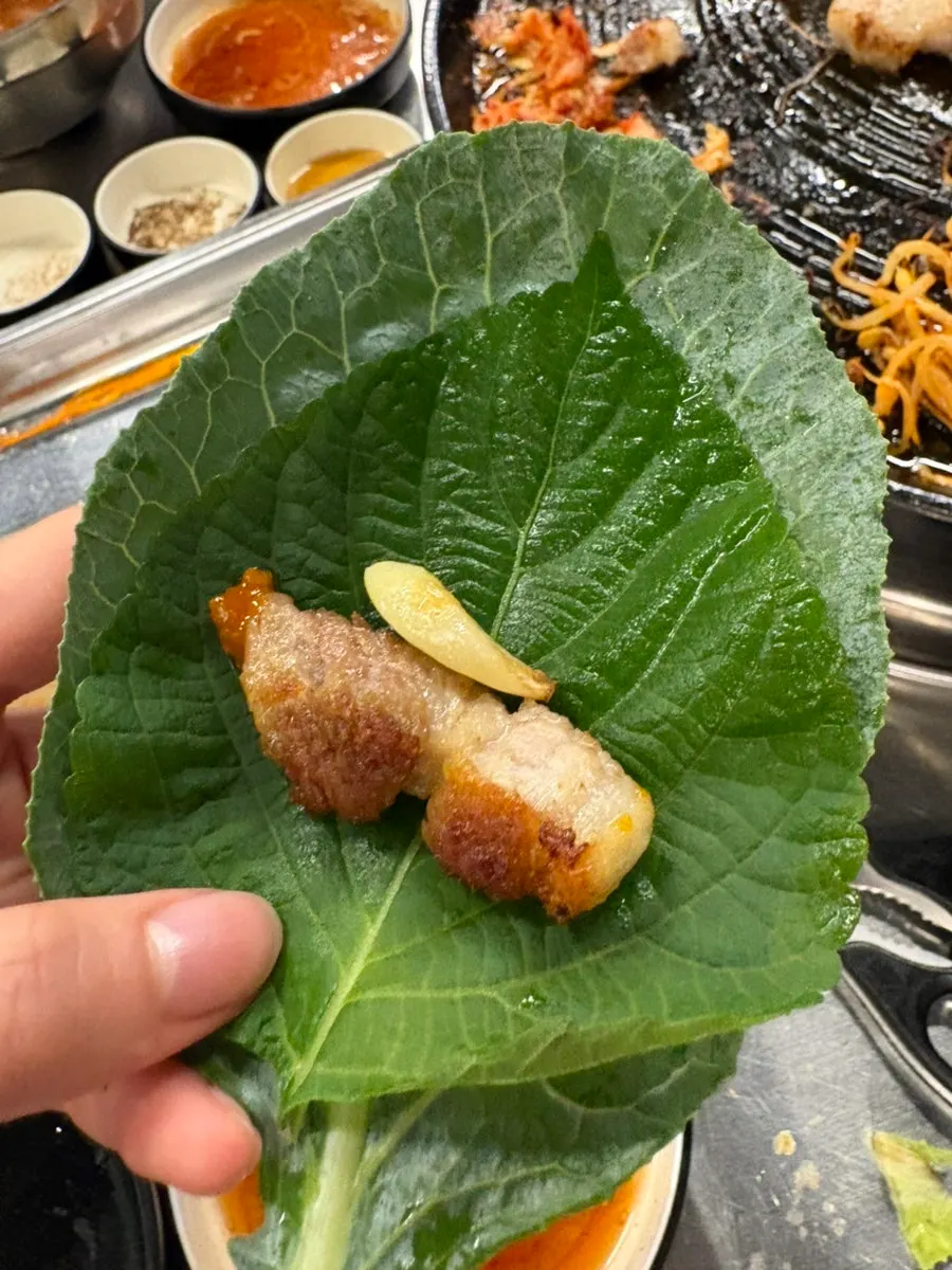 Golden-browned samgyeopsal on the cast-iron lid grill