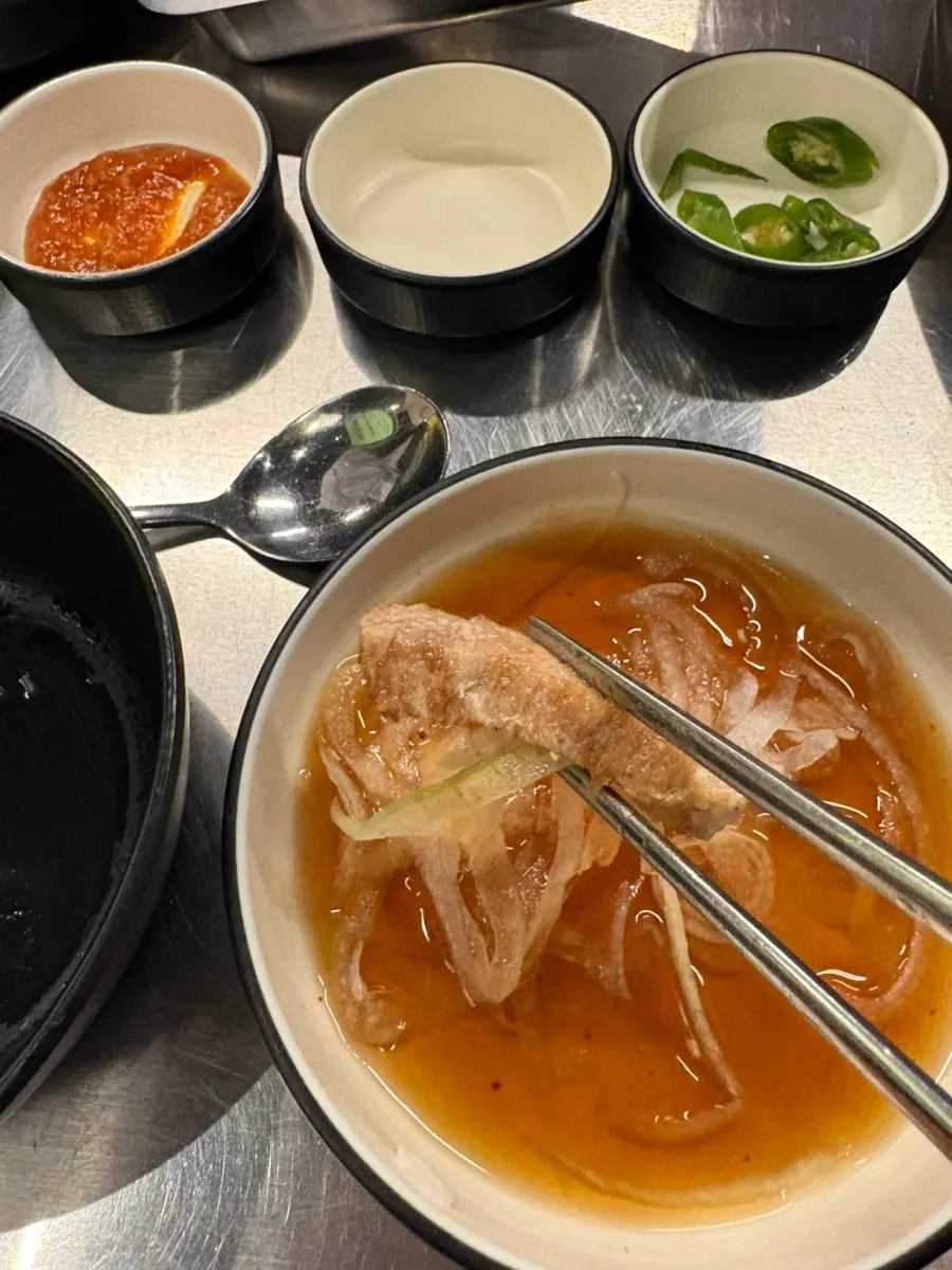 A piece of samgyeopsal placed on a cabbage wrap leaf