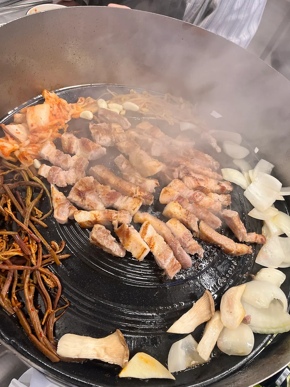 Pork belly cooking on the cast-iron lid