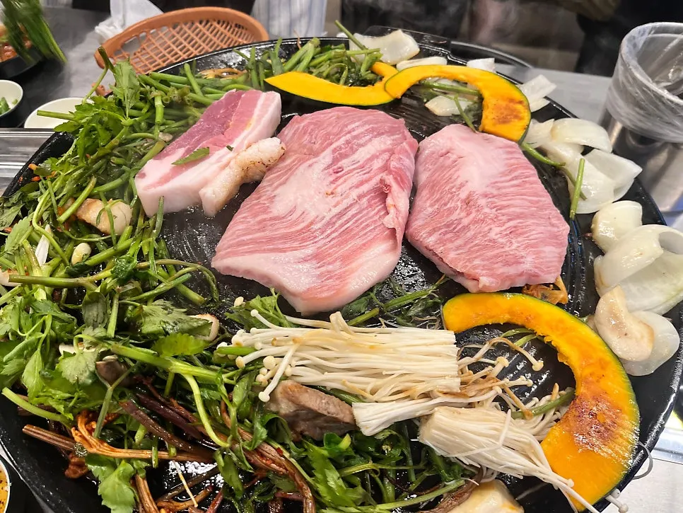 Aged kimchi and bean sprouts grilling at the edge of the cast-iron lid