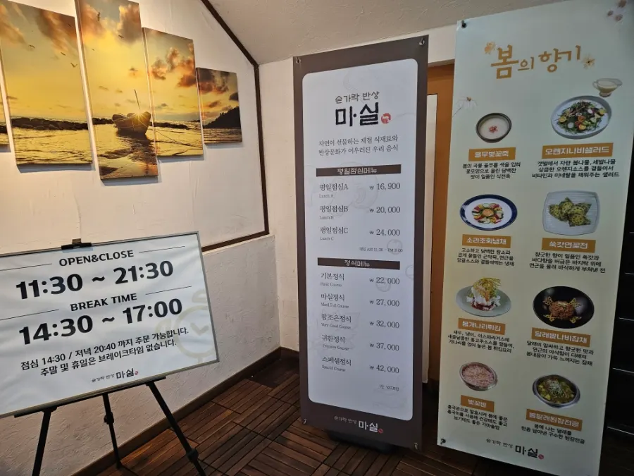 Standing sign at the entrance showing hours and menu prices