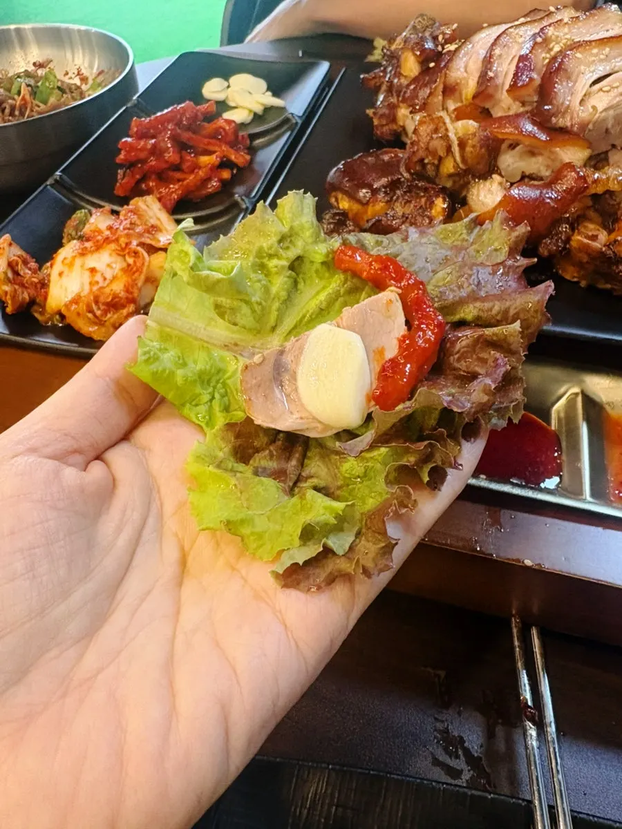 A piece of jokbal dipped in salted shrimp and ssamjang