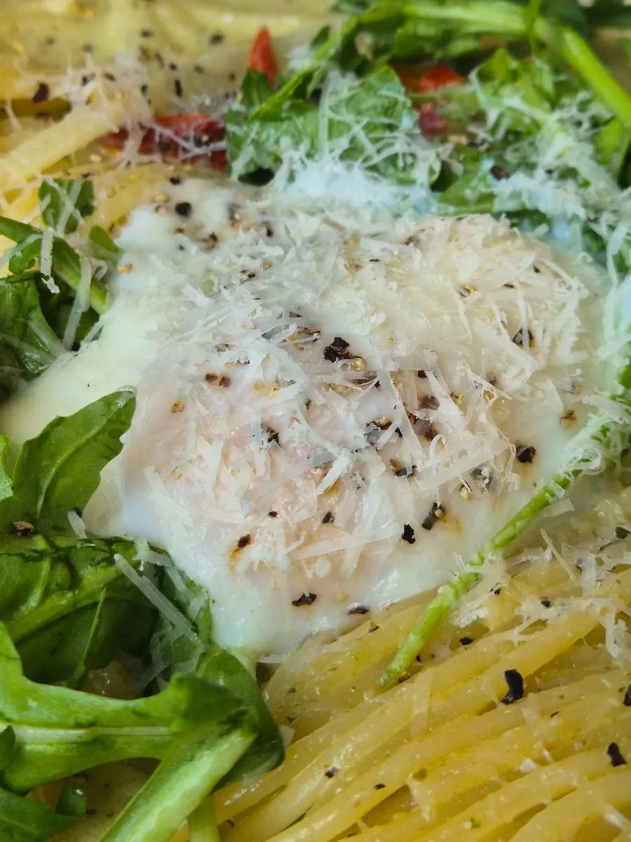 Basil cream pasta topped with a poached egg