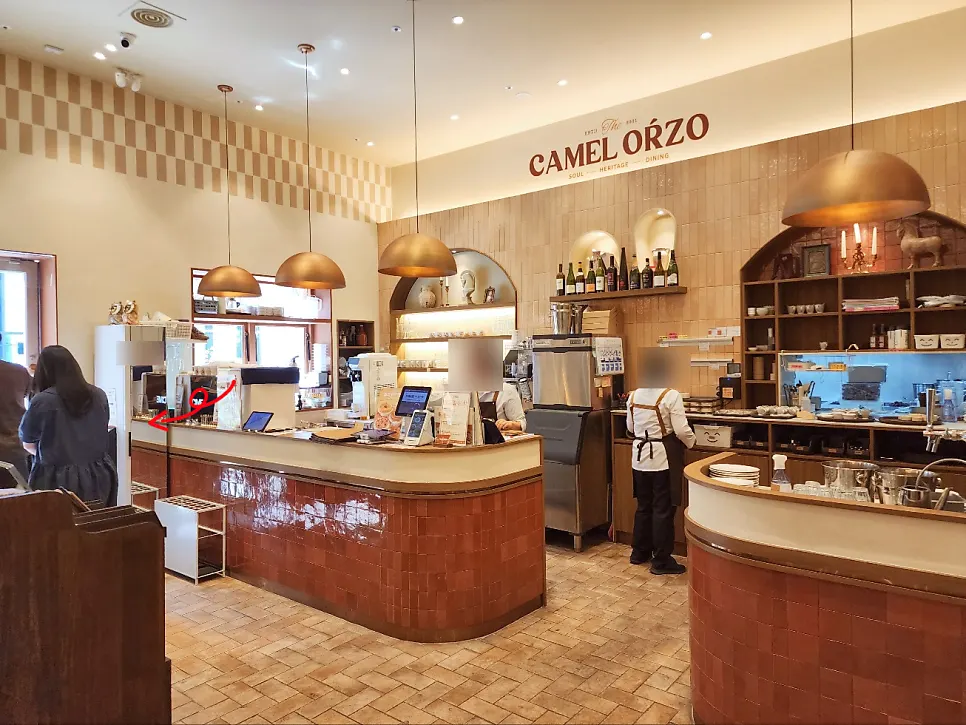 Camel Orzo's interior near the entrance with a remote queuing machine via Table Order