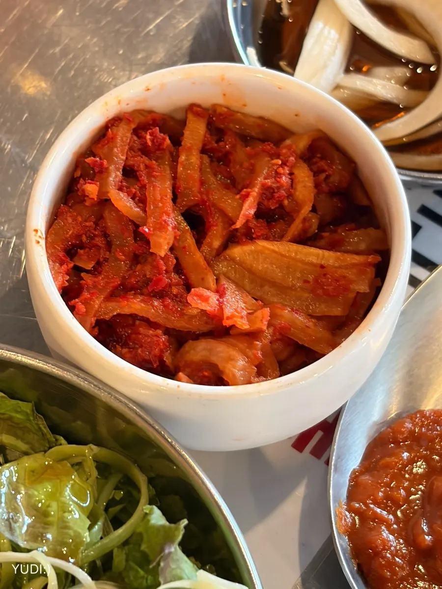 Side dishes like radish salad served alongside the meat