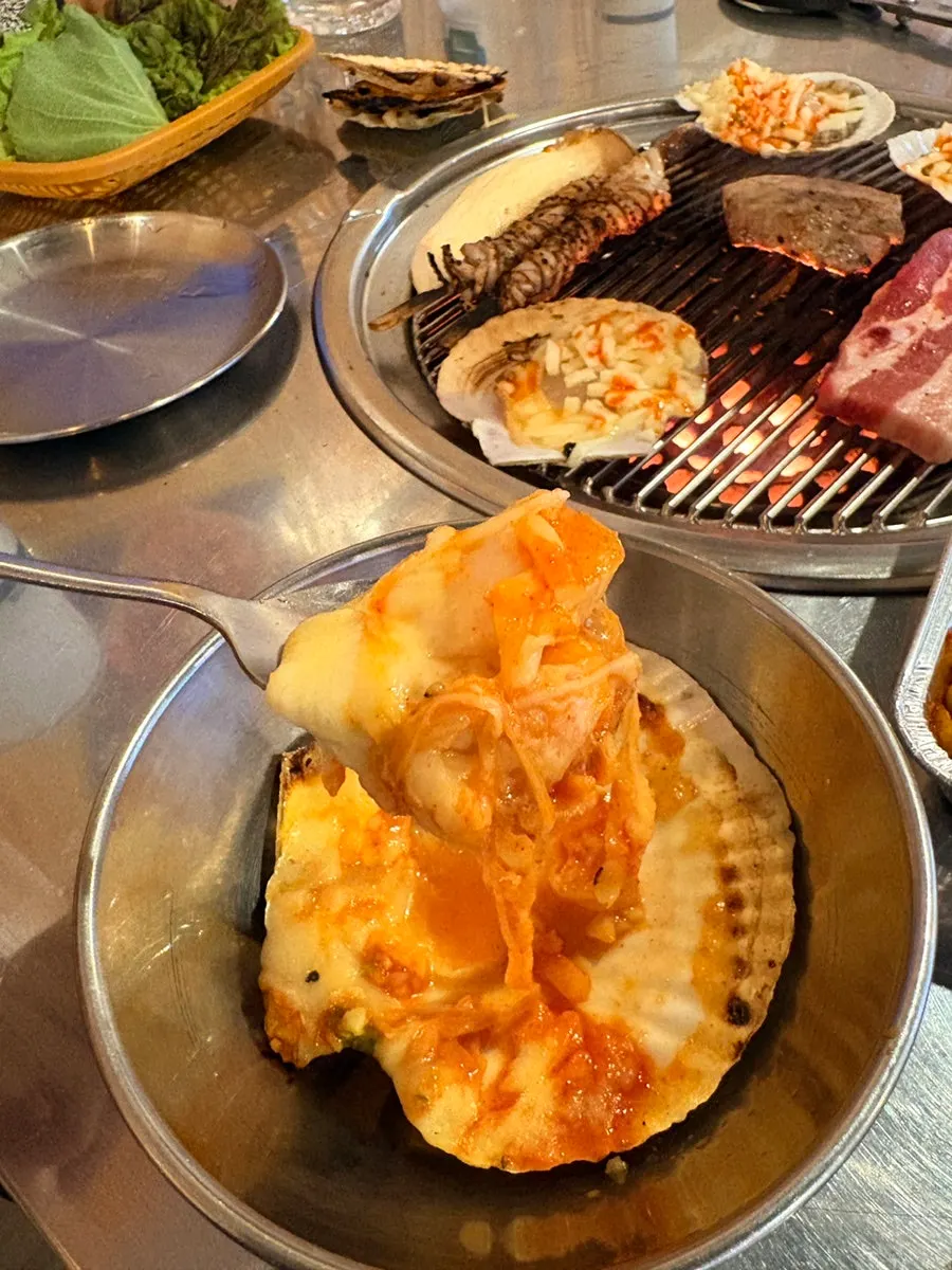 Cheese melting over grilled scallops on the grill