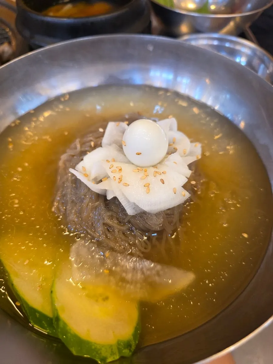 A bowl of mul-naengmyeon served alongside the meat