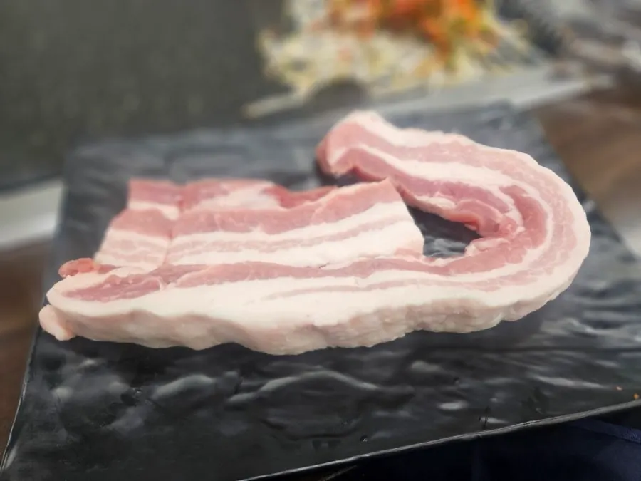 Two portions of fresh pork belly on the grill
