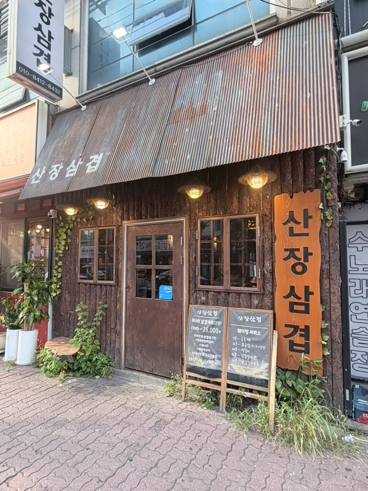 Wood-toned sign exterior of Sanjang Samgyeop Main Branch on a Baekbong-ro corner