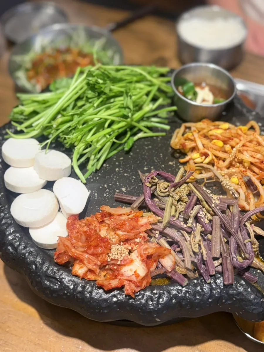 Fresh pork belly grilling on the pot lid with kimchi and bean sprouts
