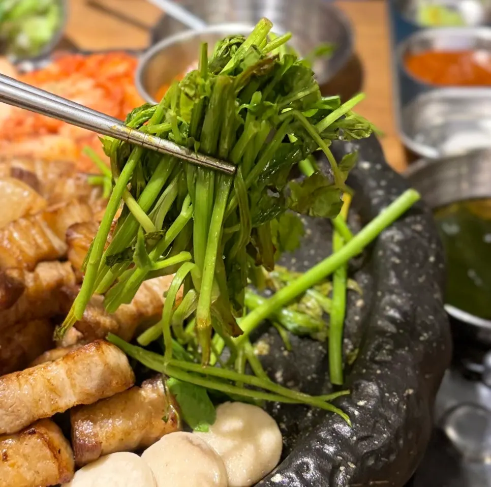 Grill topped with minari, bracken fern, kimchi, and king oyster mushroom