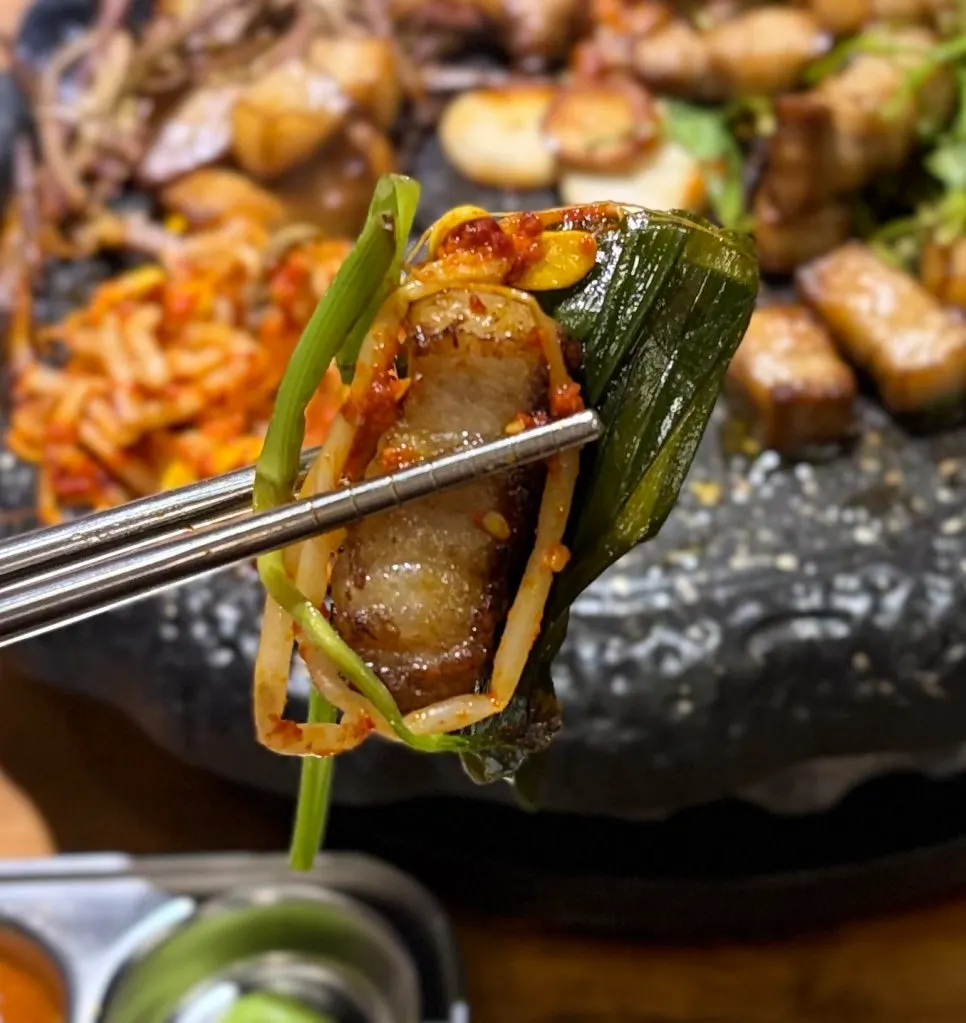 Grilled pork belly picked up with tongs