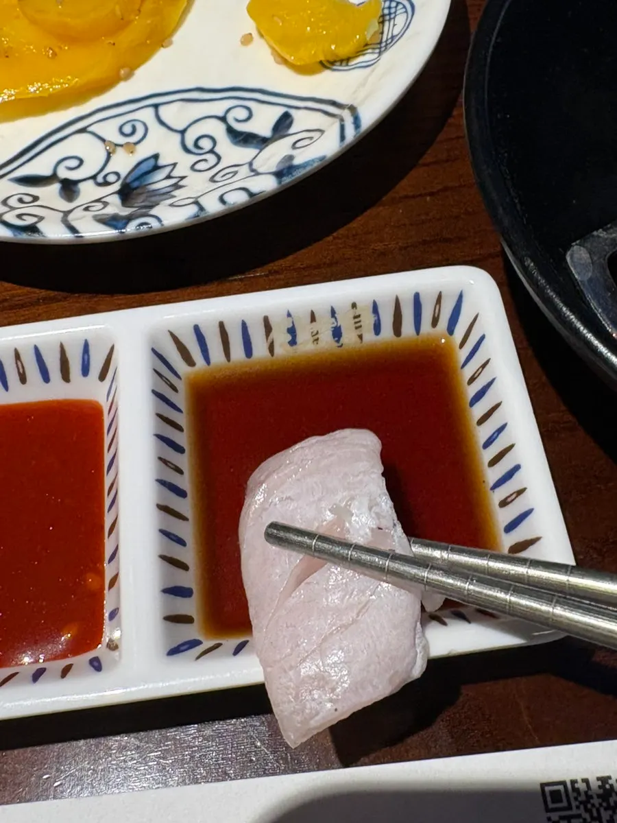 A piece of halibut sashimi topped with wasabi
