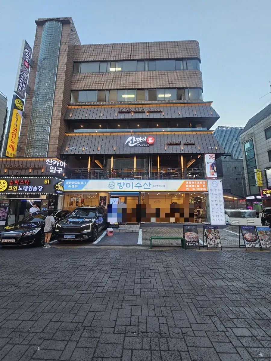원목으로 둘러진 산카이 방이점 건물 외관과 간판