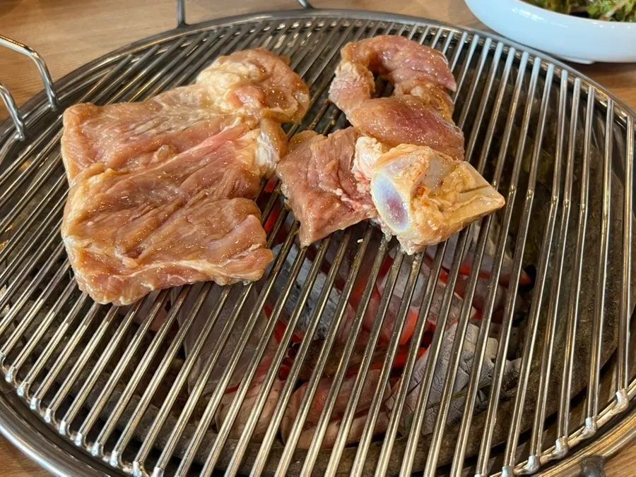 Seasoned pork ribs being grilled over charcoal