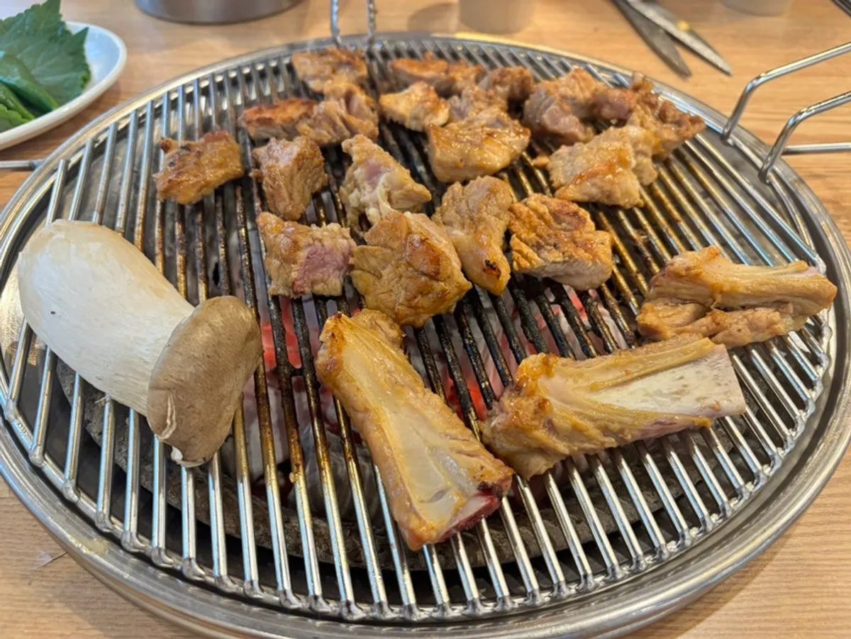 Seasoned pork galbi grilling over charcoal