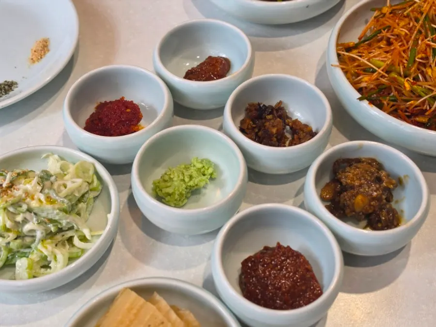 Table spread of basic side dishes with sauces and vegetables for the meat