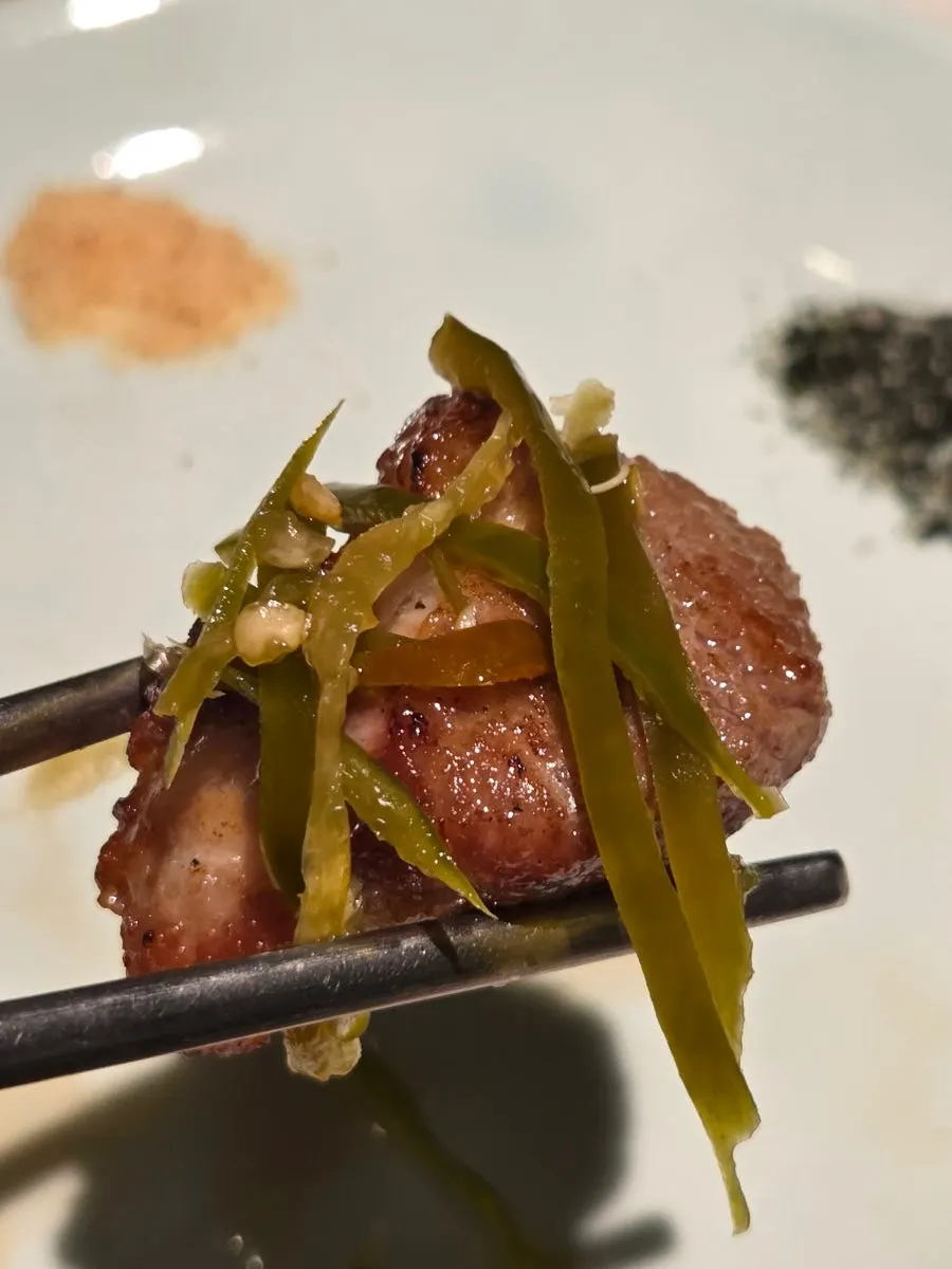 A piece of grilled pork belly dipped in salt
