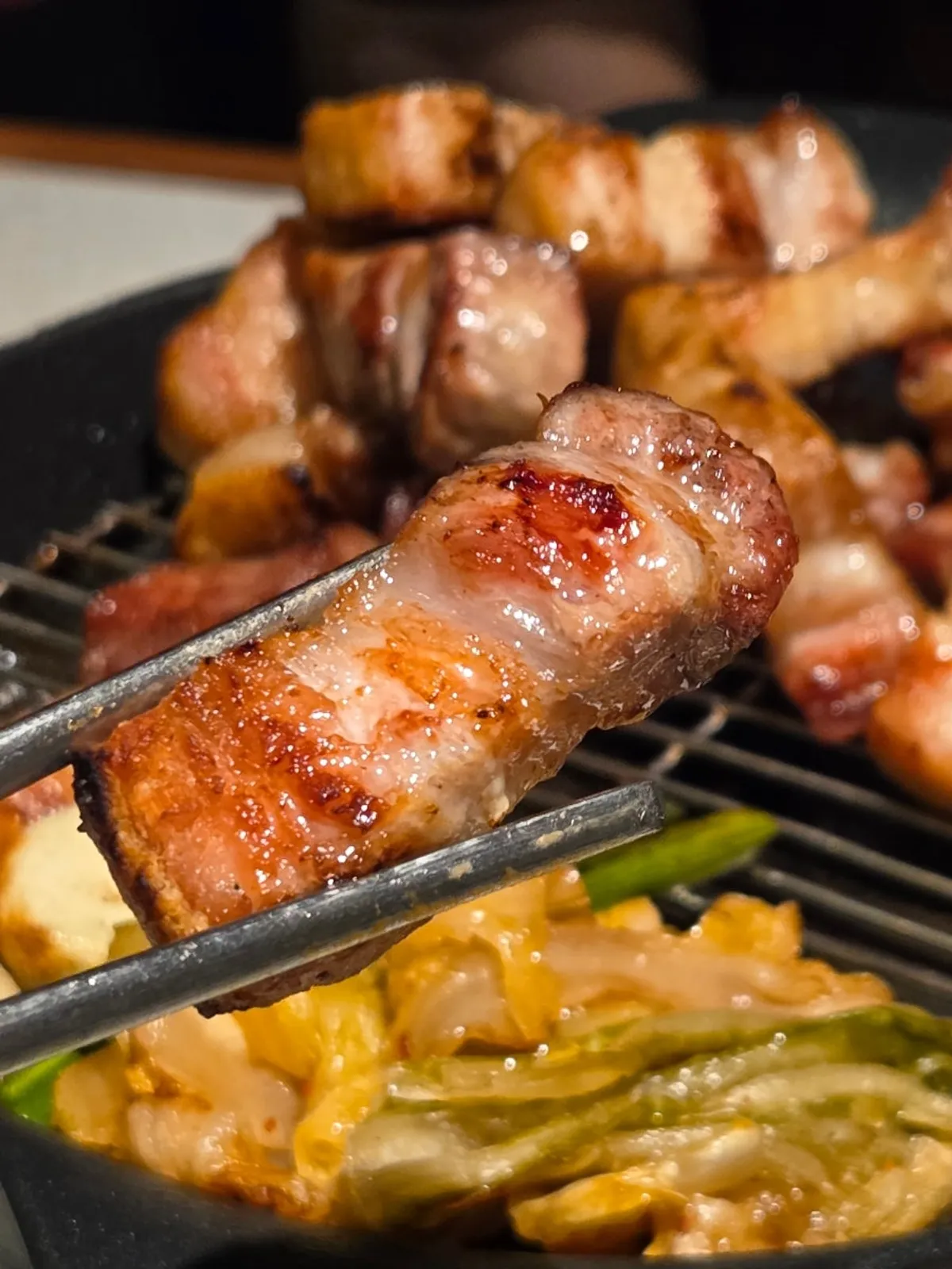 Pork belly lined up in a row on the grill