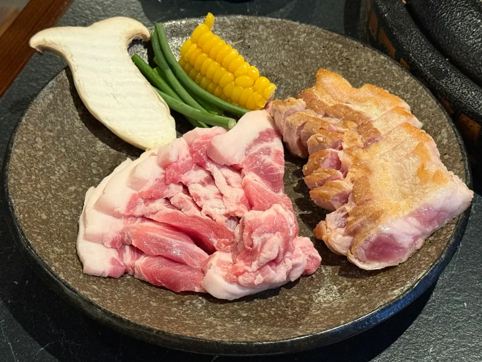 Plate of pre-seared bright red samgyeopsal and kkodeulsal