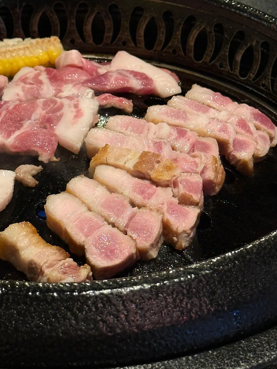 Vertical photo of kkodeulsal cooking on the grill
