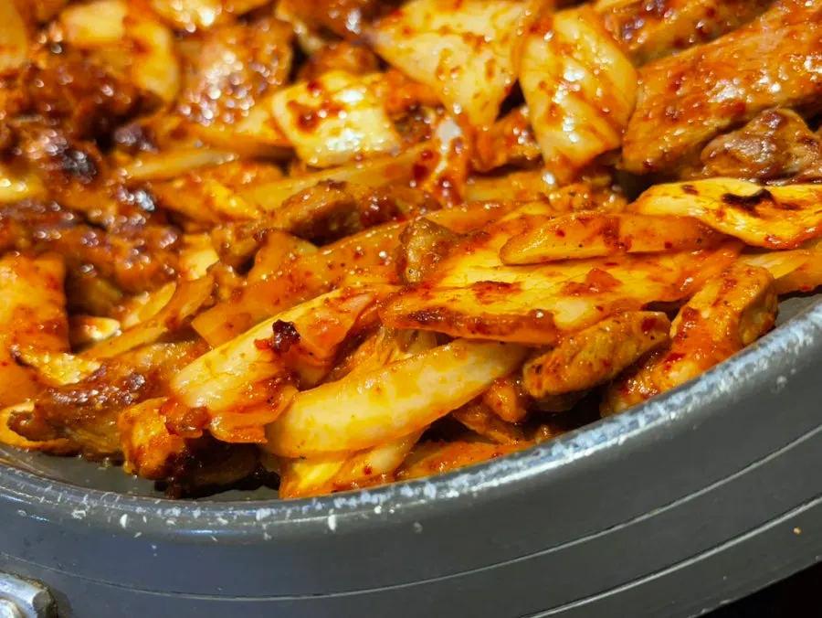 Side view of the grill piled with meat and kimchi