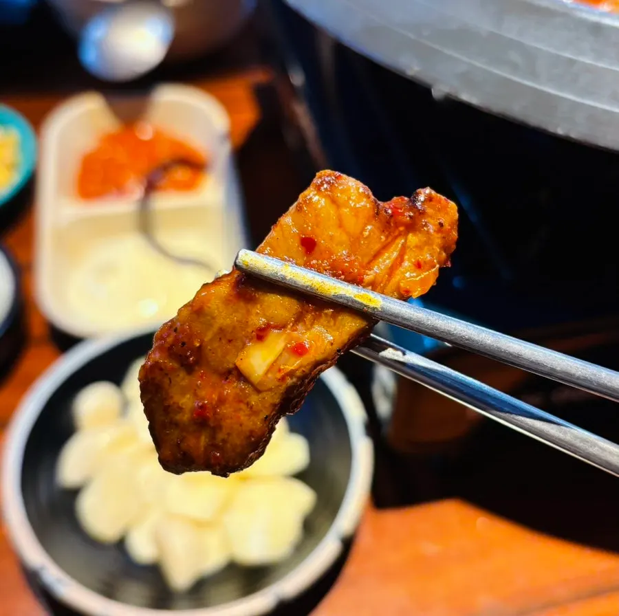 A big piece of pork picked up with tongs