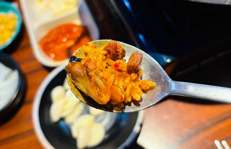 A spoonful of fried rice loaded with meat and kimchi