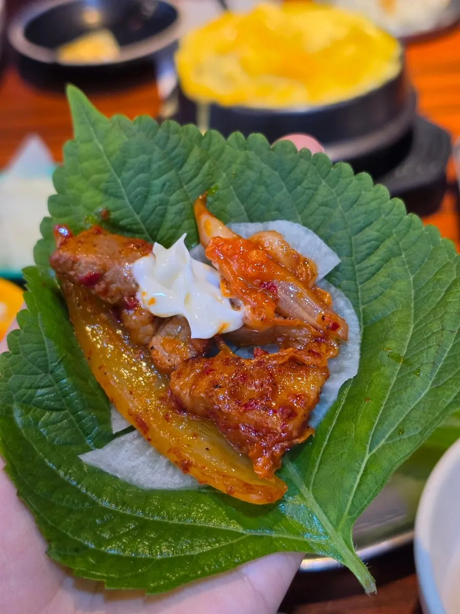 집게로 집어 올린 돼지김치구이 한 점