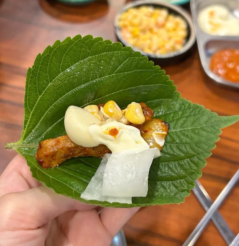 Perilla wrap topped with meat, kimchi, and pickled radish