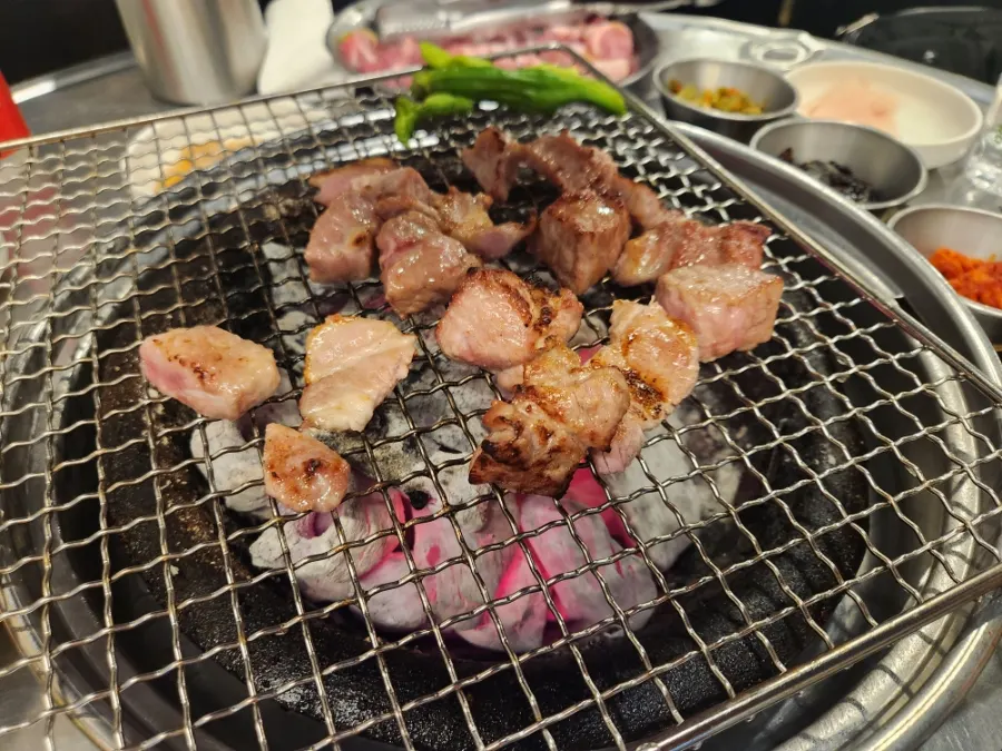 Diced shoulder cut grilling over charcoal alongside kimchi jjigae and steamed egg