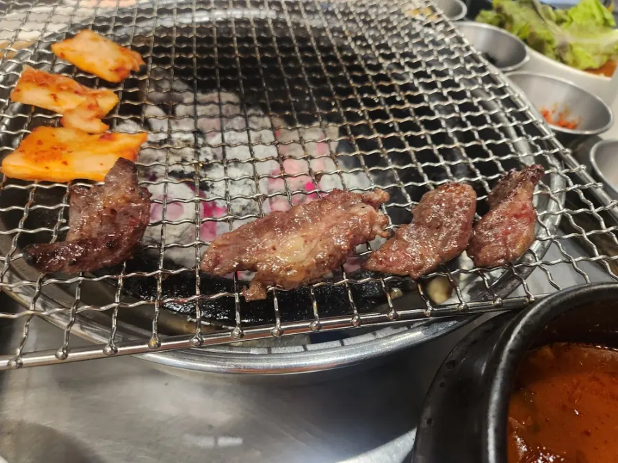 A serving of beef short ribs grilling over charcoal