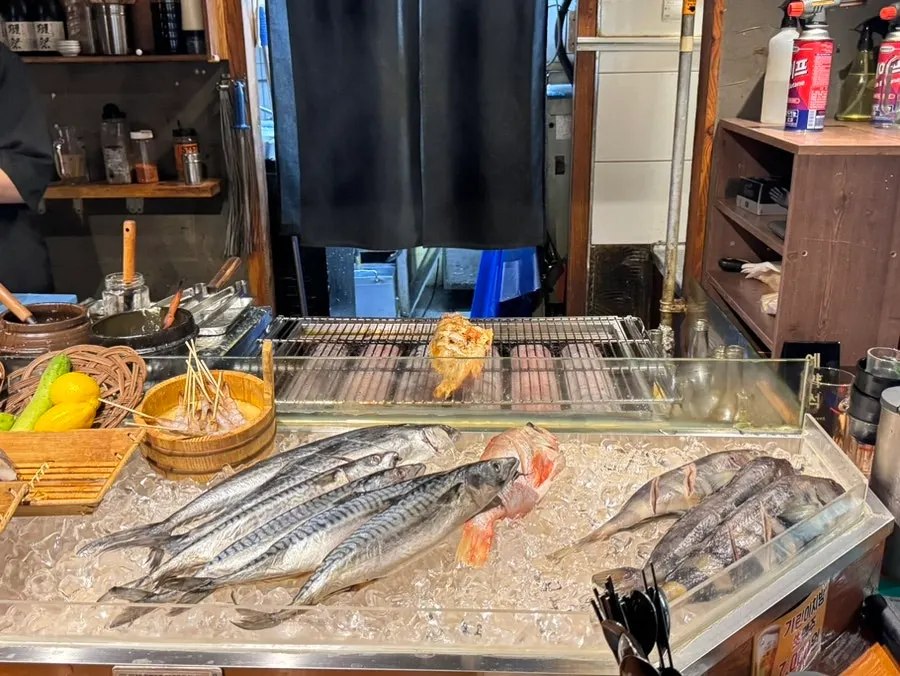 카운터 앞에 펼쳐진 생선과 꼬치 재료 진열