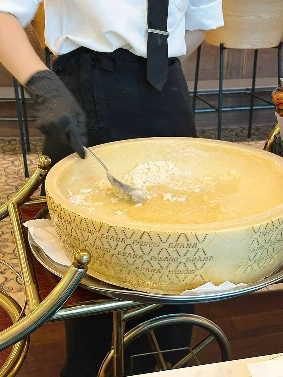 Large cheese wheel brought out to the table