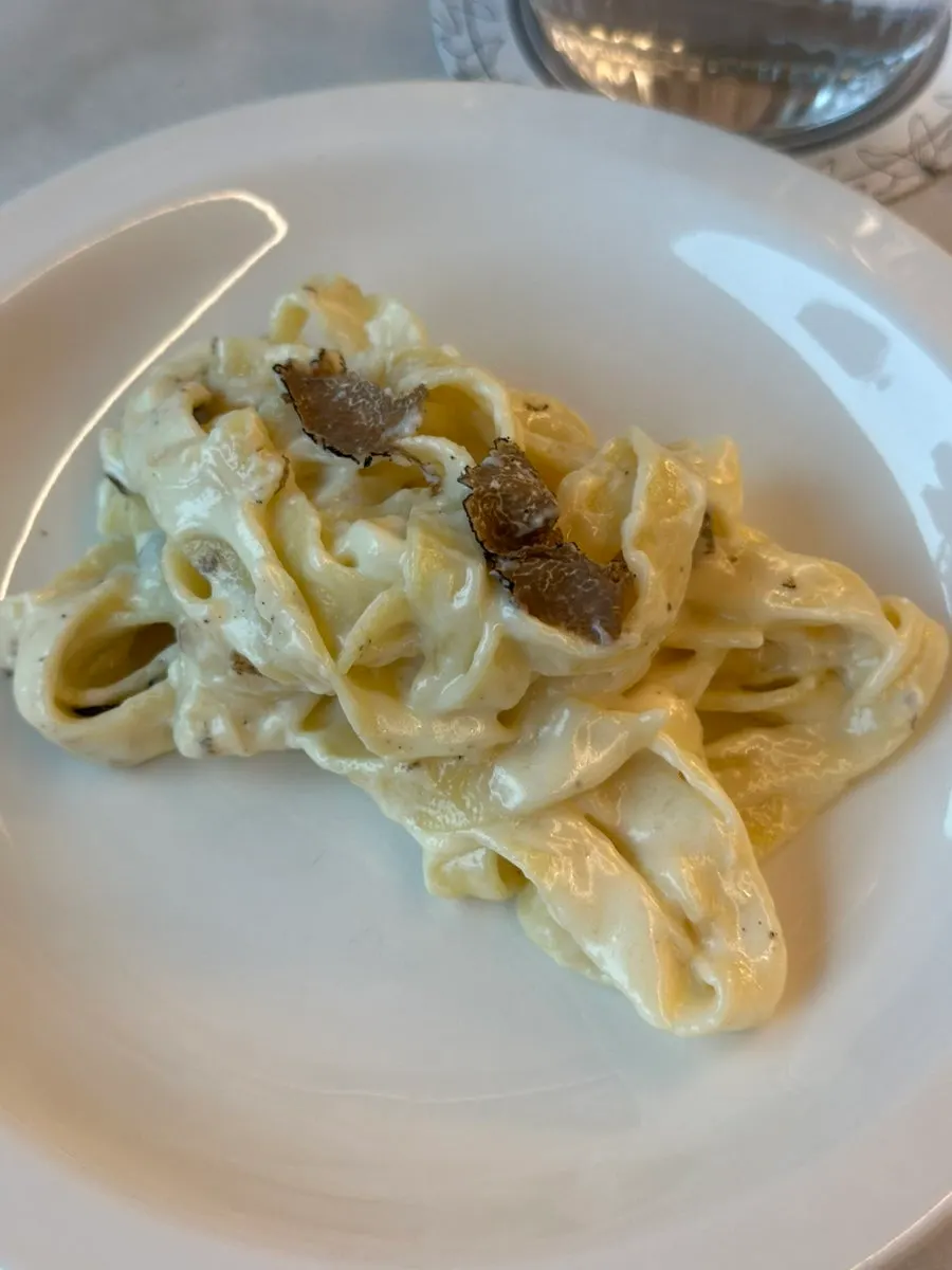 Tagliatelle being tossed inside the cheese wheel