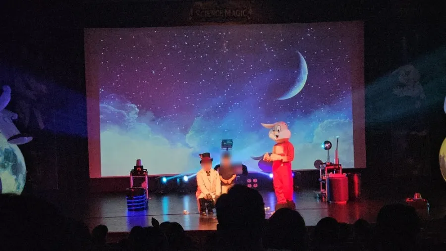 The magician walking through the audience to draw out kids' responses