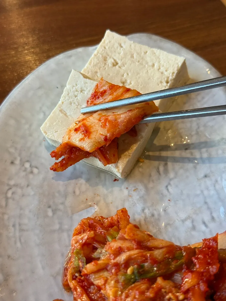 A bite of tofu topped with kimchi