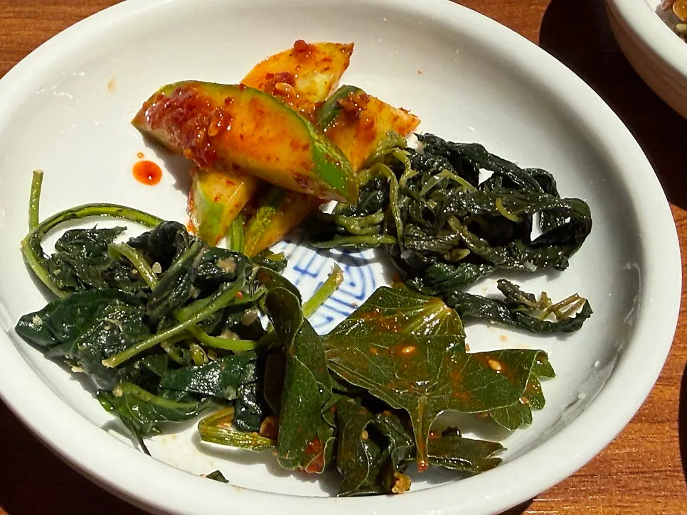 Banchan lineup with three seasoned greens and samchae namul