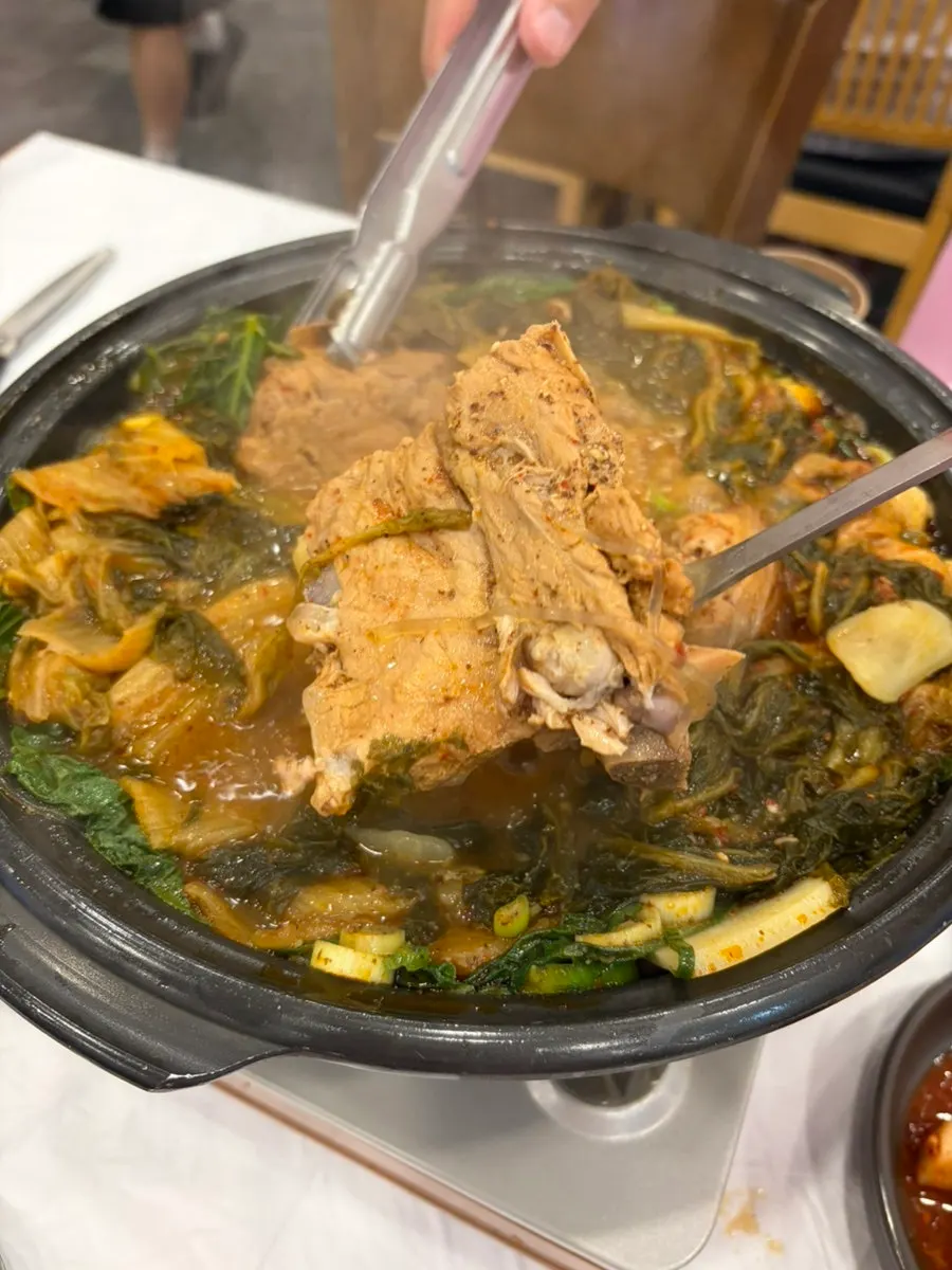 Close-up of gamjatang broth rich with perilla seeds