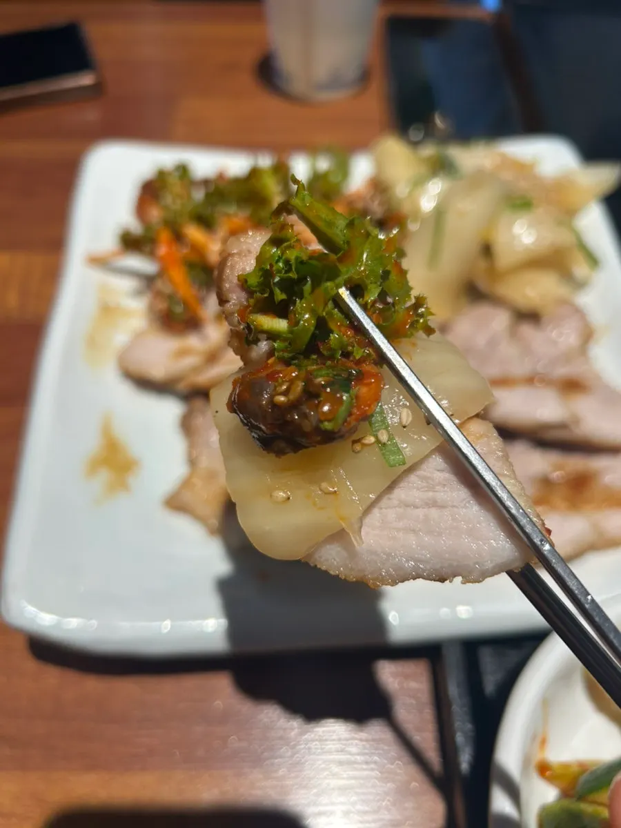 A piece of herbal boiled pork placed on aged kimchi