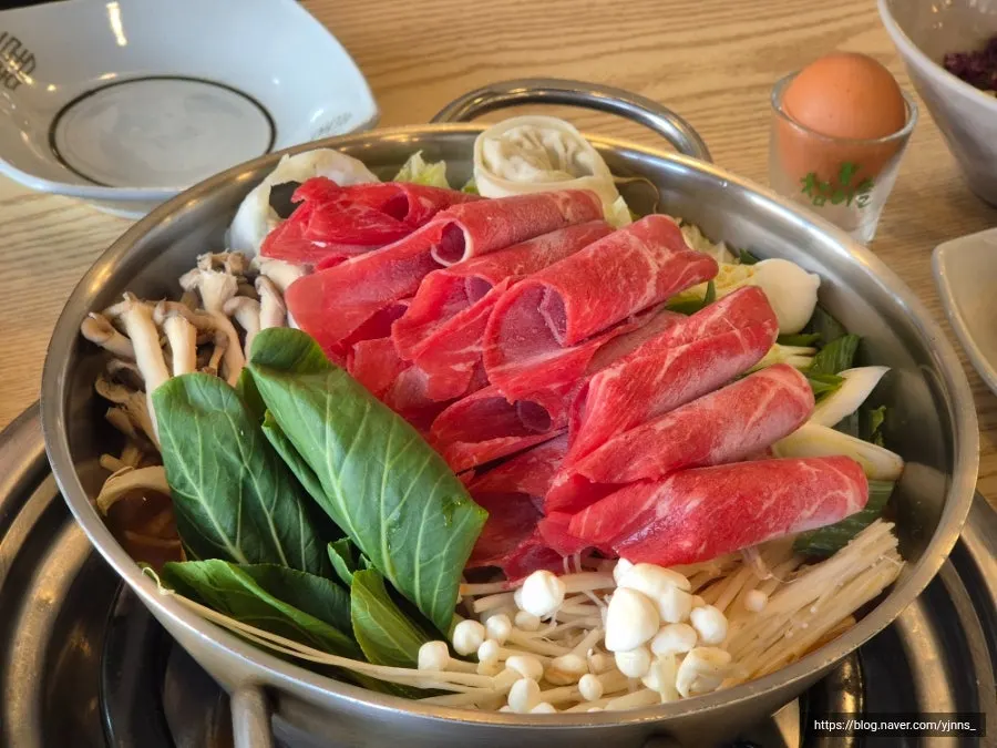 Shabu ingredients including beef neck meat and assorted vegetables and mushrooms