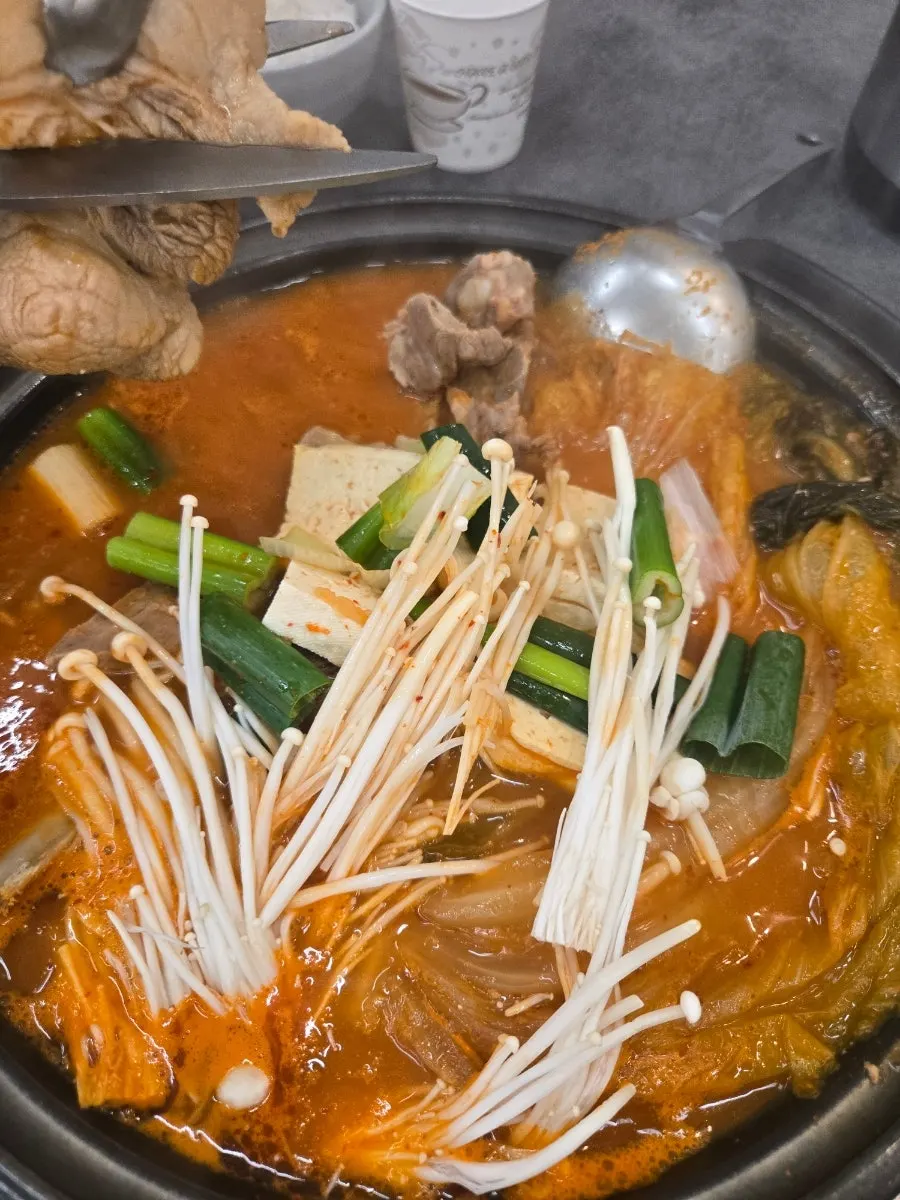 A spoonful of pot rice topped with kimchi and ribs
