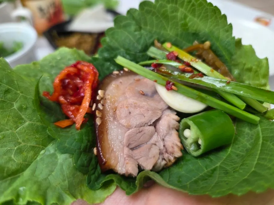 A wrap of jokbal in wrapping greens
