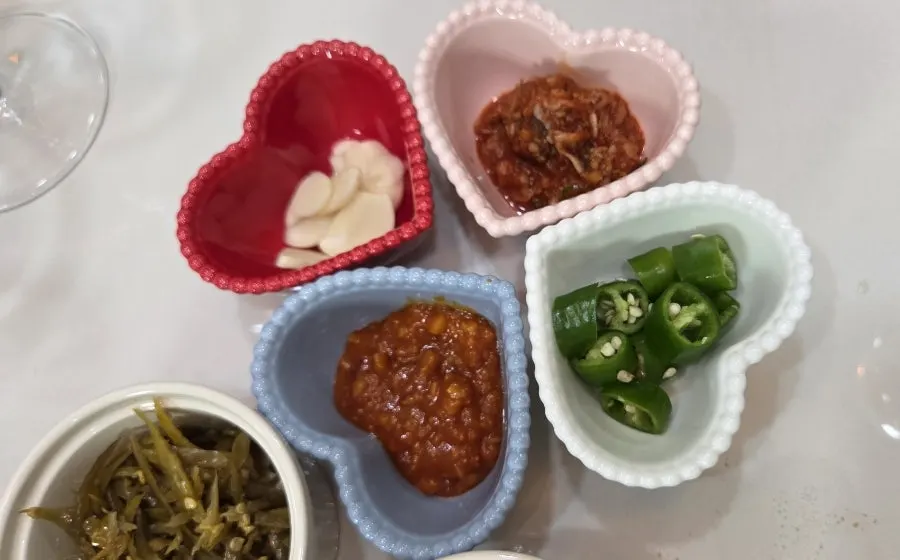 Side dishes of pickled radish and salted shrimp served alongside