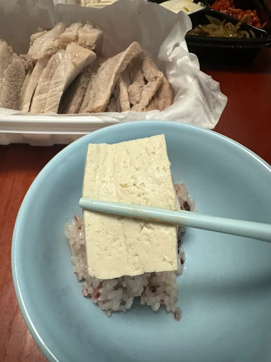A bite of tofu topped with bossam kimchi and meat