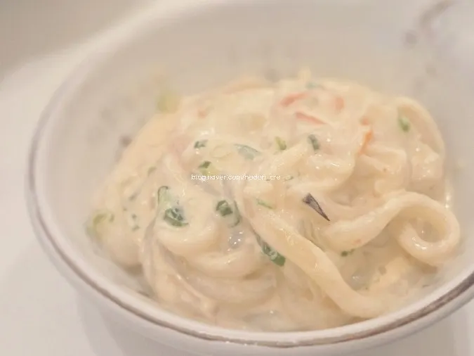 Sợi udon dày được gắp lên trong bát udon kem