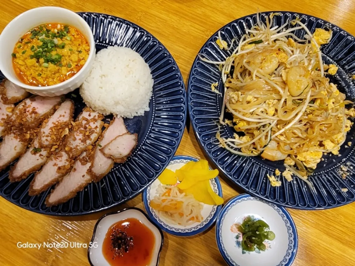 Bàn ăn với moo tod curry và pad Thái tôm