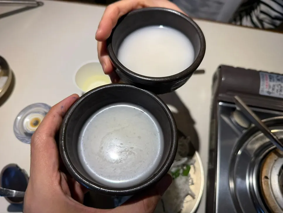 Toasting with makgeolli glasses at the dinner table
